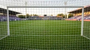 Fußballtor mit straffem Netz und einem Ball auf grünem Rasen